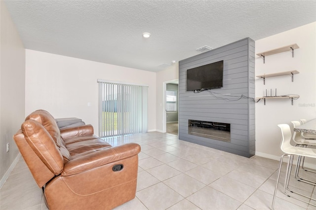 tiled living room featuring a large fireplace and a textured ceiling