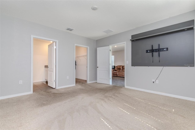 interior space featuring ensuite bathroom, a spacious closet, a closet, and carpet flooring