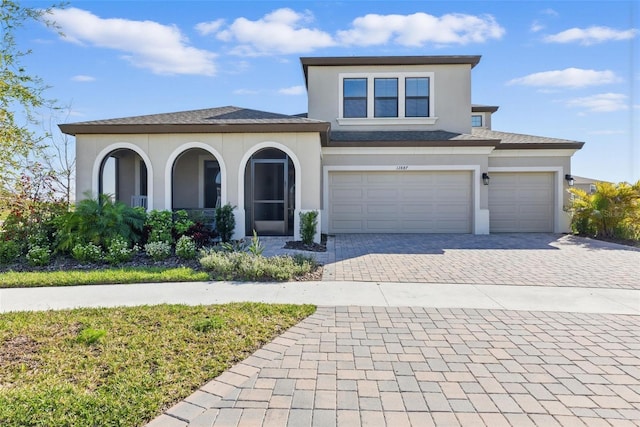 view of front facade with an attached garage, decorative driveway, and stucco siding