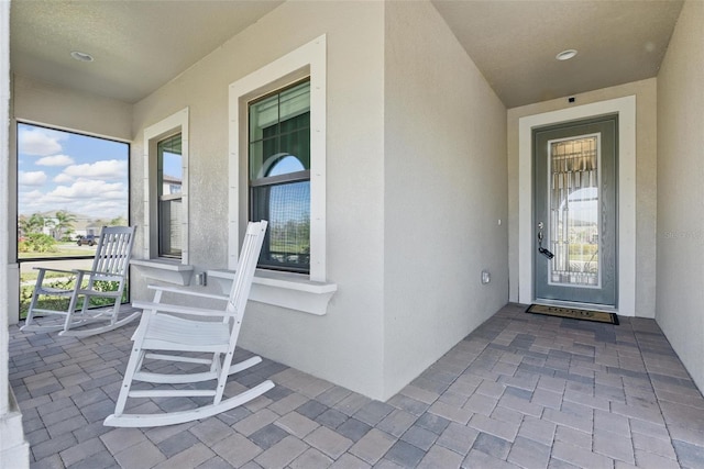 property entrance featuring covered porch and stucco siding