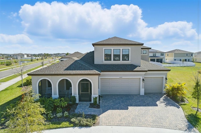 view of front of home with decorative driveway, roof with shingles, stucco siding, a garage, and a front lawn