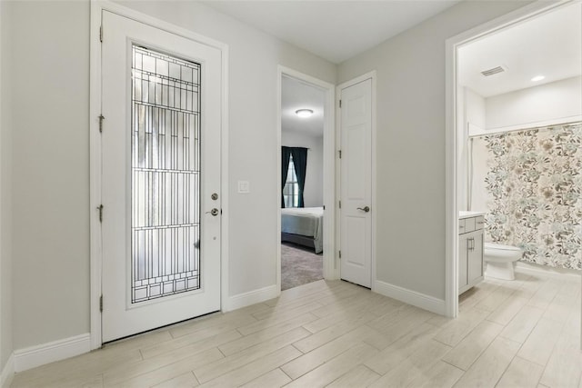 foyer entrance with visible vents, light wood-style flooring, and baseboards