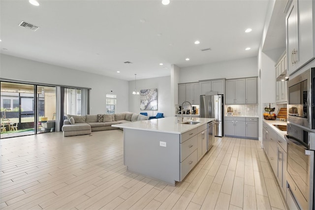 kitchen with stainless steel appliances, gray cabinets, visible vents, a healthy amount of sunlight, and a sink