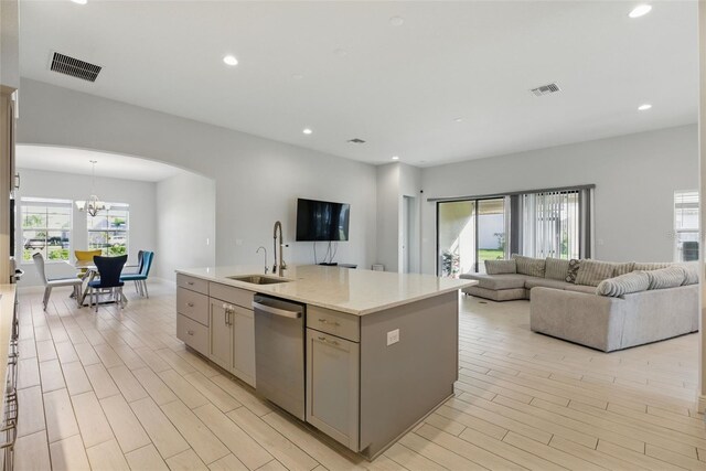 kitchen with stainless steel dishwasher, gray cabinets, a sink, and visible vents