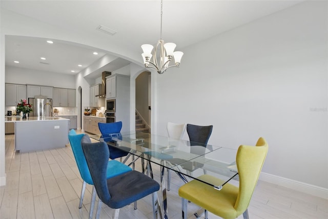 dining room with visible vents, arched walkways, light wood-style flooring, a chandelier, and recessed lighting