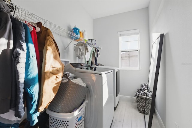 laundry room featuring laundry area, washer and clothes dryer, wood finished floors, and baseboards