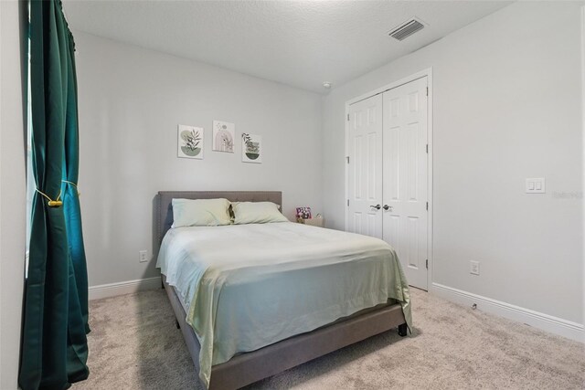 bedroom with a closet, visible vents, baseboards, and carpet flooring