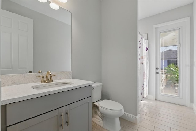 bathroom featuring a shower with shower curtain, toilet, vanity, wood finished floors, and baseboards