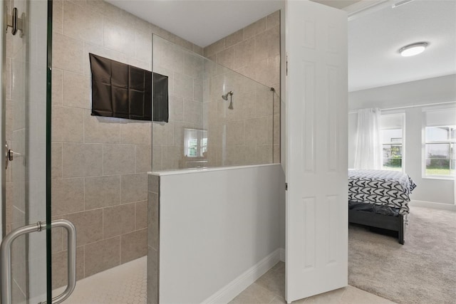 ensuite bathroom with tiled shower, connected bathroom, baseboards, and tile patterned floors