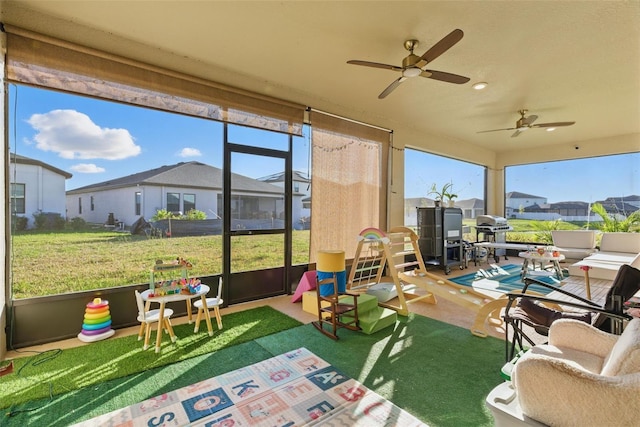 sunroom / solarium with a residential view and a ceiling fan