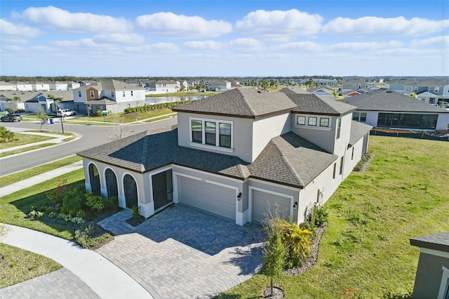 view of front of home with a residential view, decorative driveway, a front lawn, and stucco siding