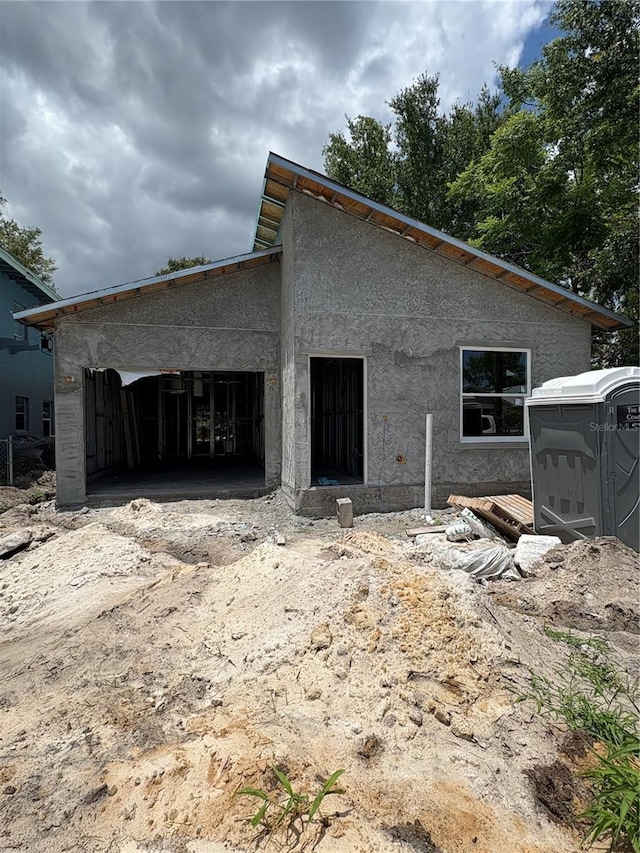 1017 Randall St, Orlando, FL 32805 - rear view of house featuring a garage, stucco siding, and dirt driveway