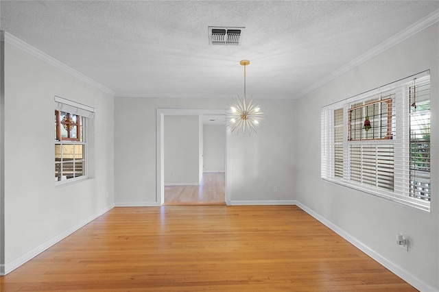 spare room with ornamental molding, light hardwood / wood-style floors, a textured ceiling, and a notable chandelier