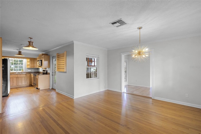 unfurnished living room with sink, a notable chandelier, light hardwood / wood-style floors, crown molding, and a textured ceiling