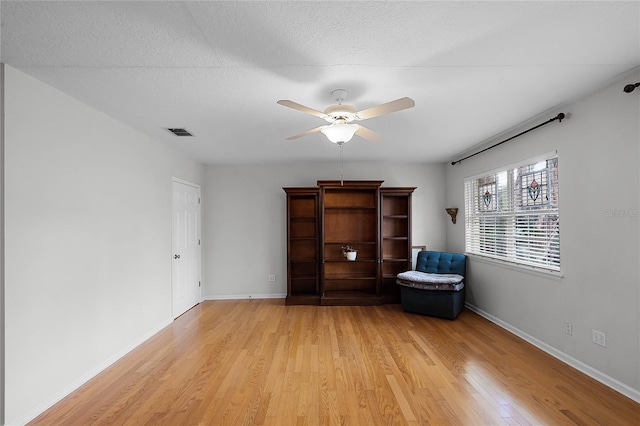 unfurnished room featuring ceiling fan, light hardwood / wood-style floors, and a textured ceiling