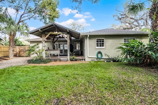 back of property featuring french doors, a yard, and a wooden deck