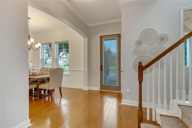 foyer with baseboards, stairs, ornamental molding, wood-type flooring, and an inviting chandelier