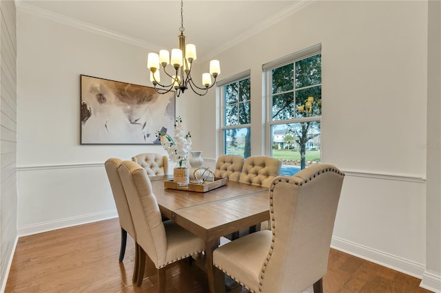 dining room featuring a notable chandelier, crown molding, baseboards, and wood finished floors