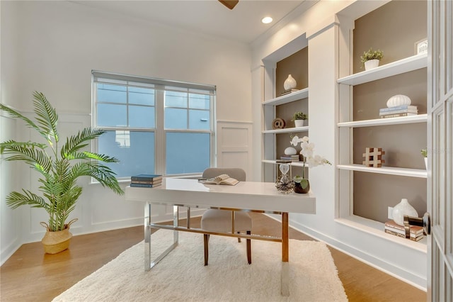 office space featuring a wainscoted wall, a decorative wall, wood finished floors, and built in features