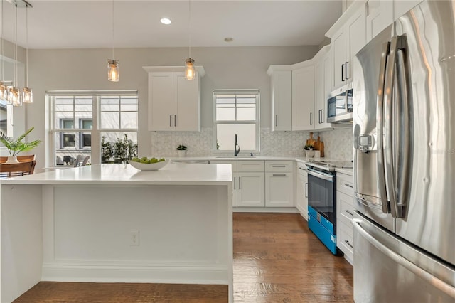 kitchen with dark wood-style flooring, stainless steel appliances, light countertops, backsplash, and a sink