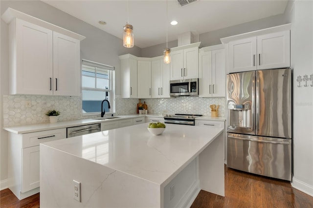 kitchen featuring white cabinets, stainless steel appliances, a sink, and a center island