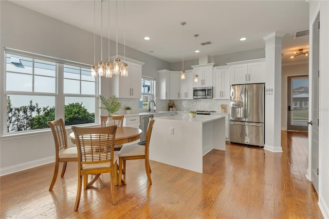 kitchen with stainless steel appliances, light countertops, visible vents, decorative backsplash, and a sink