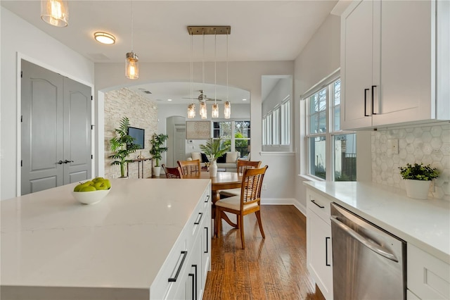 kitchen featuring arched walkways, dark wood-style floors, white cabinets, backsplash, and dishwasher