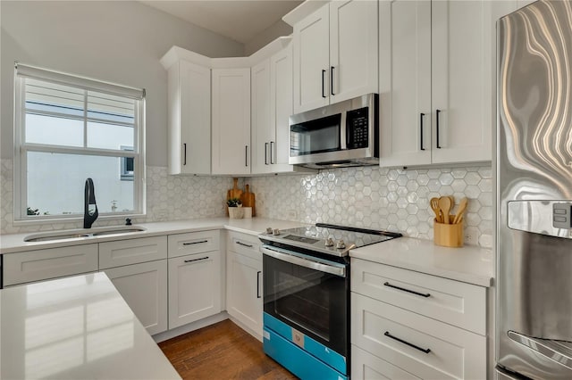 kitchen featuring backsplash, appliances with stainless steel finishes, light countertops, and a sink