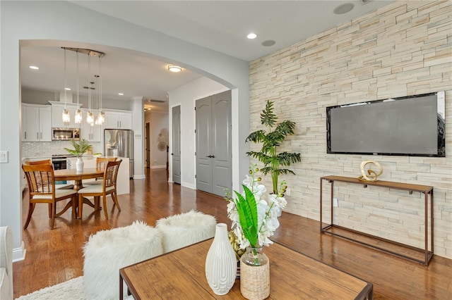 living room with arched walkways, baseboards, recessed lighting, and wood finished floors