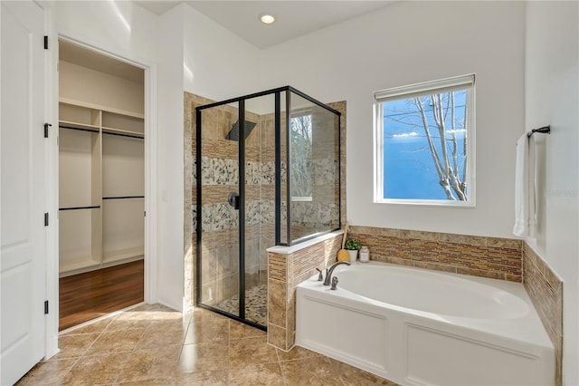 bathroom featuring a shower stall, a walk in closet, a bath, and tile patterned floors