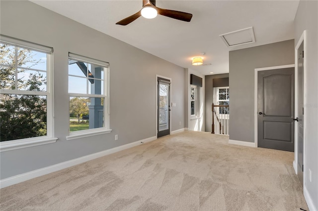 carpeted spare room with a wealth of natural light, attic access, and baseboards