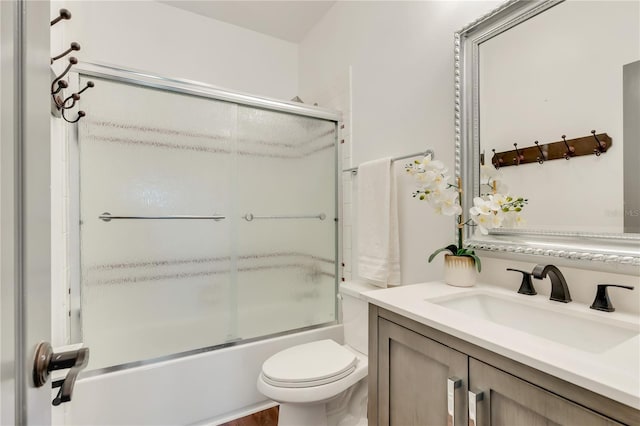 full bathroom with toilet, bath / shower combo with glass door, and vanity