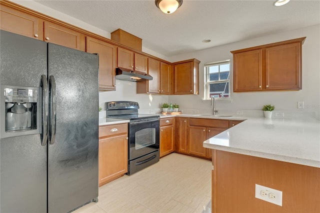 kitchen featuring black appliances, under cabinet range hood, brown cabinets, and a sink