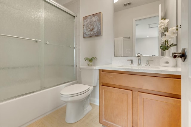 full bath with toilet, bath / shower combo with glass door, vanity, and visible vents