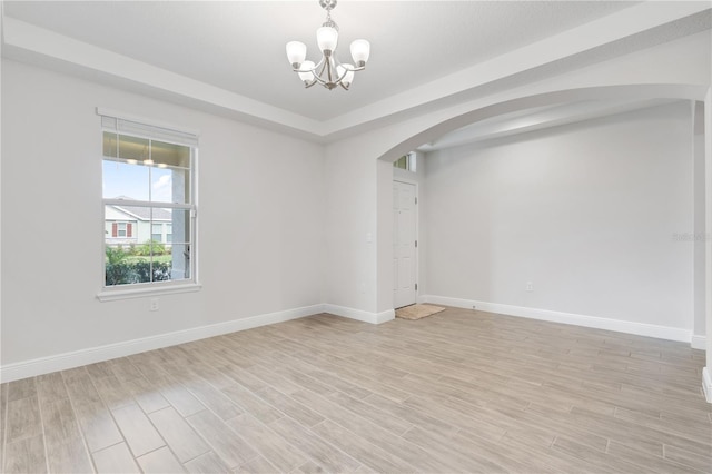 empty room featuring a chandelier and light wood-type flooring