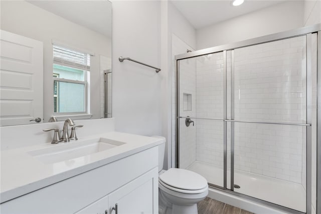 bathroom featuring vanity, toilet, a shower with door, and wood-type flooring