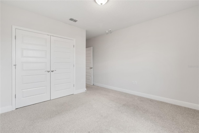 unfurnished bedroom featuring a closet, carpet, and a textured ceiling