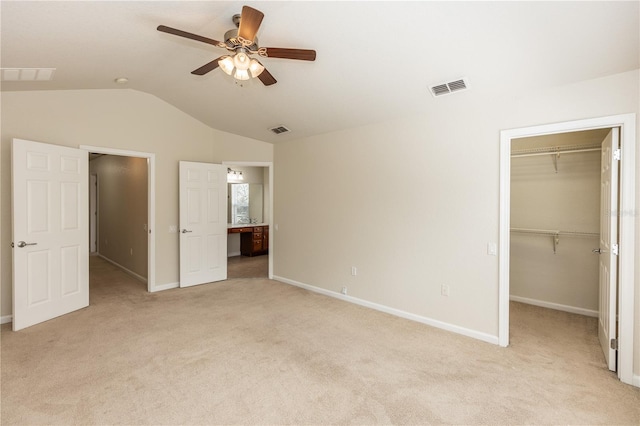 unfurnished bedroom featuring a closet, lofted ceiling, a spacious closet, and light carpet