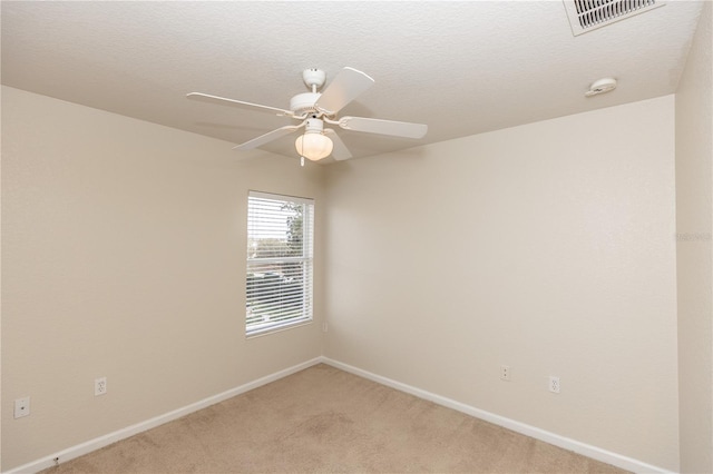 empty room with ceiling fan, light colored carpet, and a textured ceiling