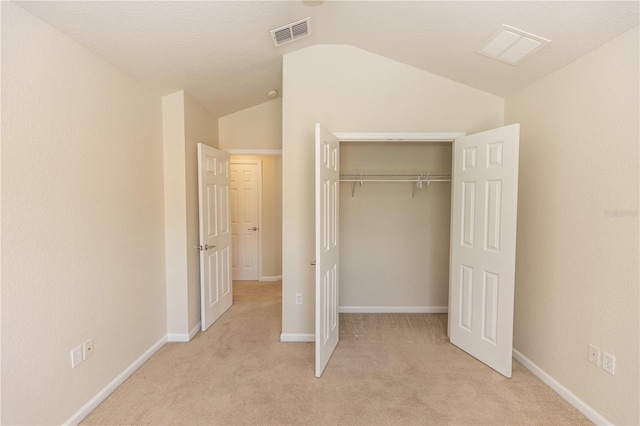 unfurnished bedroom with lofted ceiling, light colored carpet, and a closet