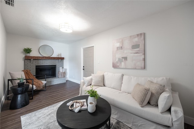 living room with a brick fireplace, dark hardwood / wood-style floors, and a textured ceiling