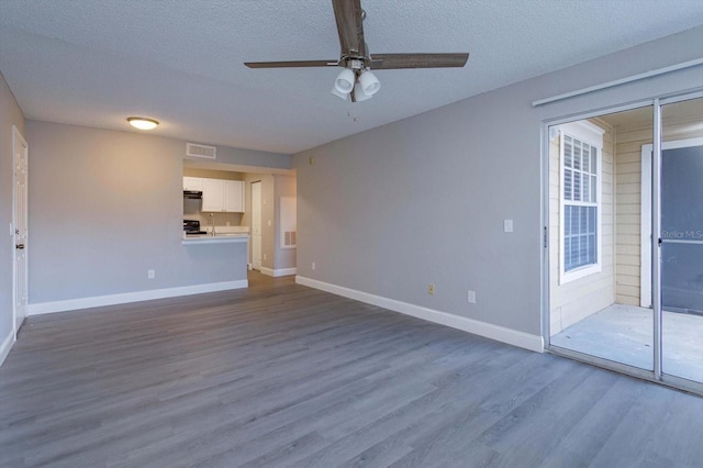 unfurnished living room with ceiling fan, hardwood / wood-style flooring, and a textured ceiling