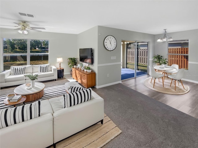 living room featuring ceiling fan with notable chandelier and hardwood / wood-style flooring