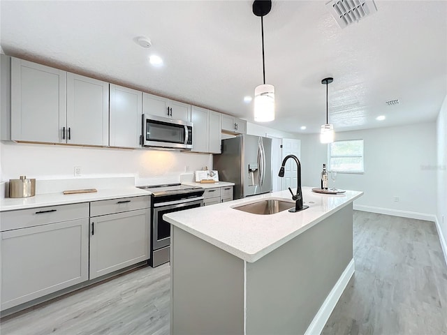 kitchen featuring pendant lighting, sink, gray cabinets, appliances with stainless steel finishes, and a kitchen island with sink