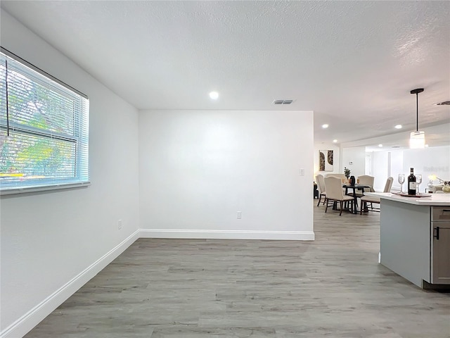 spare room with light hardwood / wood-style floors and a textured ceiling