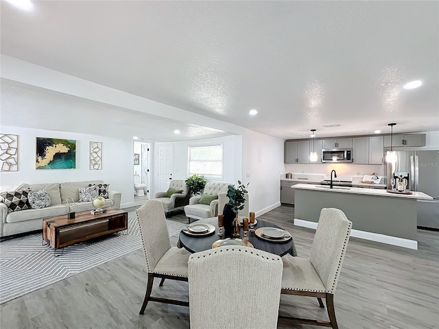 dining area featuring sink, light hardwood / wood-style floors, and a textured ceiling