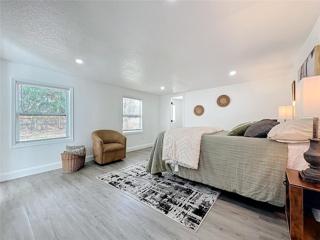 bedroom featuring light hardwood / wood-style floors and a textured ceiling