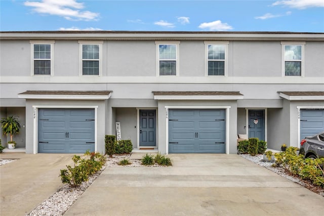 view of property featuring an attached garage, concrete driveway, and stucco siding