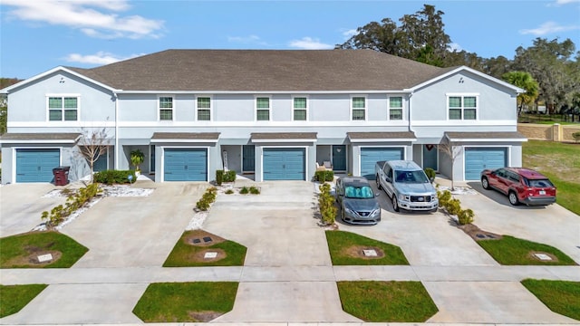 multi unit property featuring driveway, an attached garage, and stucco siding