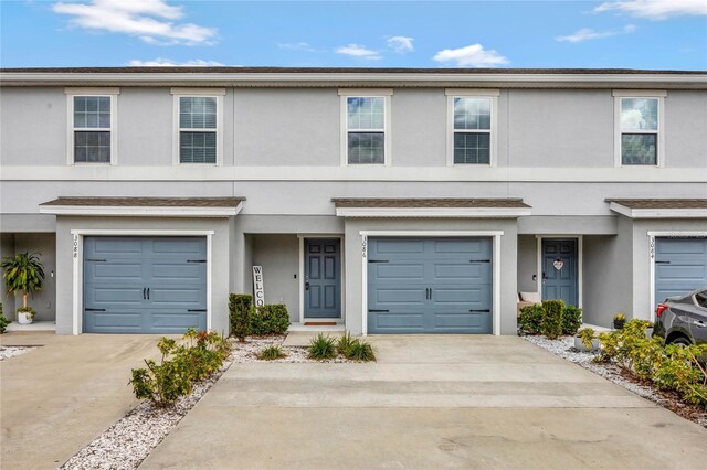 multi unit property featuring concrete driveway, an attached garage, and stucco siding